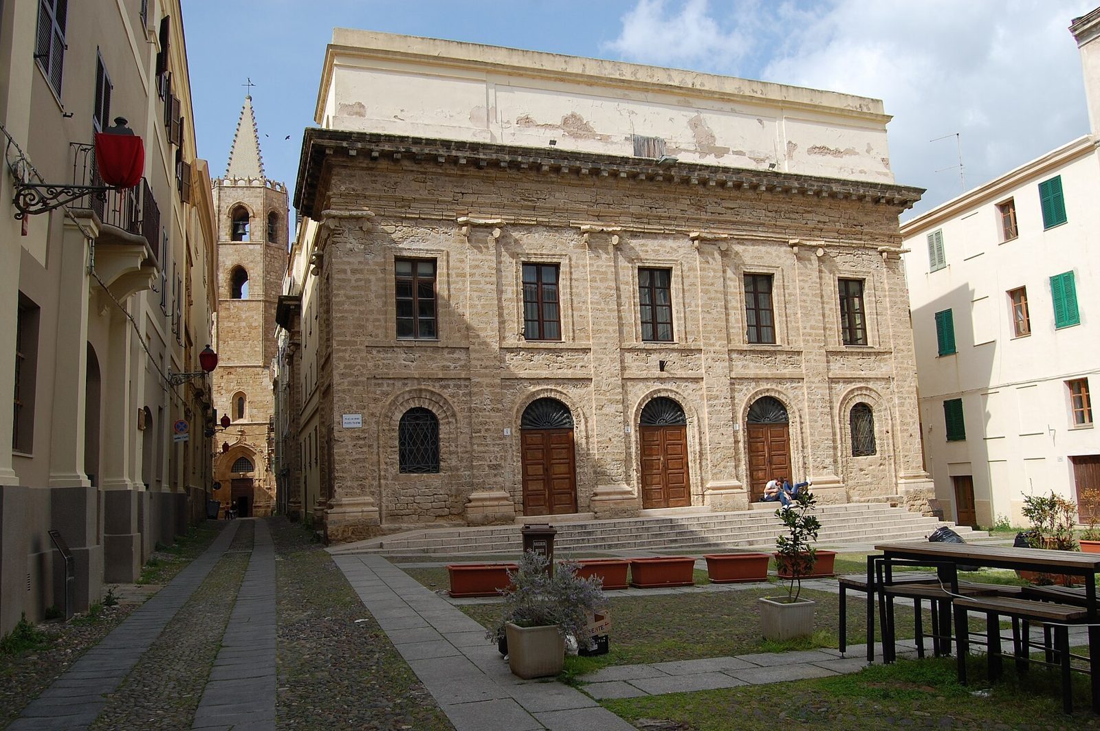 Lanterne avvolte nei drappi rossi della Settimana Santa in una piazza del centro storico di Alghero, con il campanile della cattedrale sullo sfondo